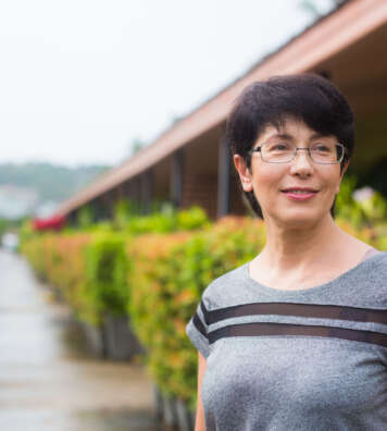 Close-up portrait of beautiful woman standing on the street while looking at camera and smiling.