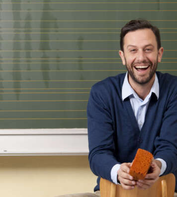Laughing teacher in classroom at blackboard