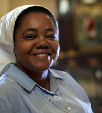 Woman and religion, portrait of catholic nun praying in church and looking at camera