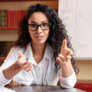 Online Video Chat. Portrait of female English teacher sitting at table, wearing glasses, having virtual conference, recording webinar, talking to camera, gesturing to webcam. Lady explaining theme